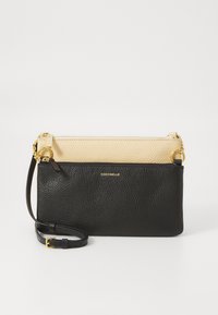 Borsa a polso in pelle bicolore beige e nera con hardware dorato e tracolla regolabile, con logo "Coccinelle" sulla sezione nera.