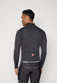 Schwarzes Langarm-Radsporttrikot mit hohem Kragen und einer Rückentasche, aus einem glatten, dehnbaren Stoff. Weißer Akzent am Saum.