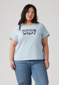 Ανοιχτό μπλε κοντομάνικο μπλουζάκι με λουλουδάτο λογότυπο Levi's σε σκούρο φόντο. Μαλακό ύφασμα με άνετη εφαρμογή.