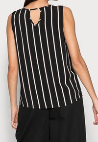 Bezrukávý černý top s vertikálními bílými a růžovými pruhy, s detailem v zakulaceném výstřihu na zádech a volným střihem. Hladká textilie.