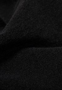 Black fleece fabric, soft texture, with a slight sheen. The material appears dense and slightly fuzzy, showing subtle variations in the surface.