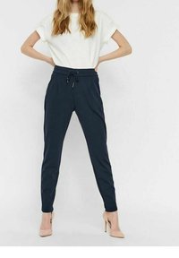 Marinblå joggerbyxor med dragsko i midjan, sidofickor och tapered ben, kombinerat med en löst sittande vit t-shirt och nude-häften.