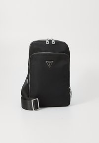 Bolso bandolera de nylon negro con cremalleras plateadas, logo triangular, correa ajustable y bolsillo con cremallera en la parte frontal. Forma rectangular compacta.