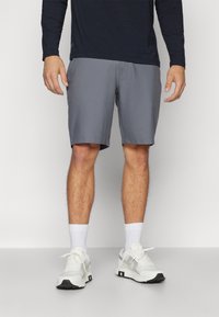 Menns grå sporty shorts med en glatt tekstur, over knelengde, kombinert med hvite sneakers og ankelsokker.