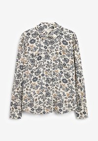 Blouse à manches longues crème avec un motif floral noir et beige, col volé et boutonnage à l'avant, posée à plat sur un fond blanc.