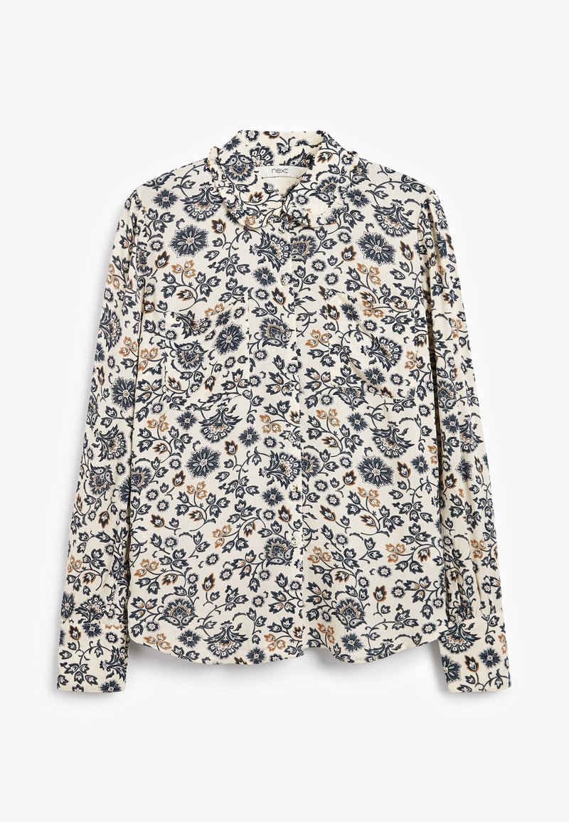 Blouse à manches longues crème avec un motif floral noir et beige, col volé et boutonnage à l'avant, posée à plat sur un fond blanc.