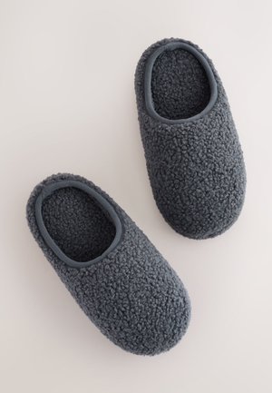 Zapatillas de casa de forro polar gris con superficie texturizada, forma redondeada y diseño de talón abierto. Rematadas con una tela gris suave.
