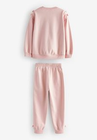 Helles rosa Sweatshirt und passende Hose, hergestellt aus weichem Stoff. Das Sweatshirt hat elastische Bündchen und kleine Schleifenakzente an den Ärmeln.