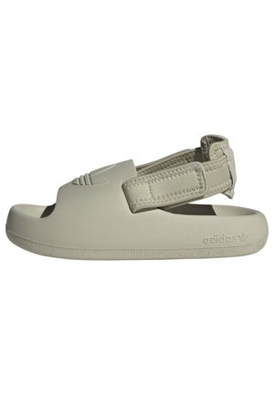 Jasnobeżowa sandałka Adidas z odkrytymi palcami, regulowanym paskiem wokół pięty i wytłoczonym logo po boku podeszwy.