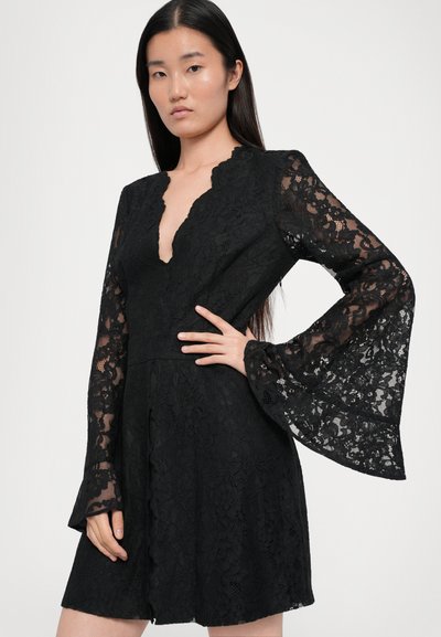 Black lace dress with long, flared sleeves and a deep V-neckline. Intricate floral pattern throughout. Fitted bodice with a flared skirt.