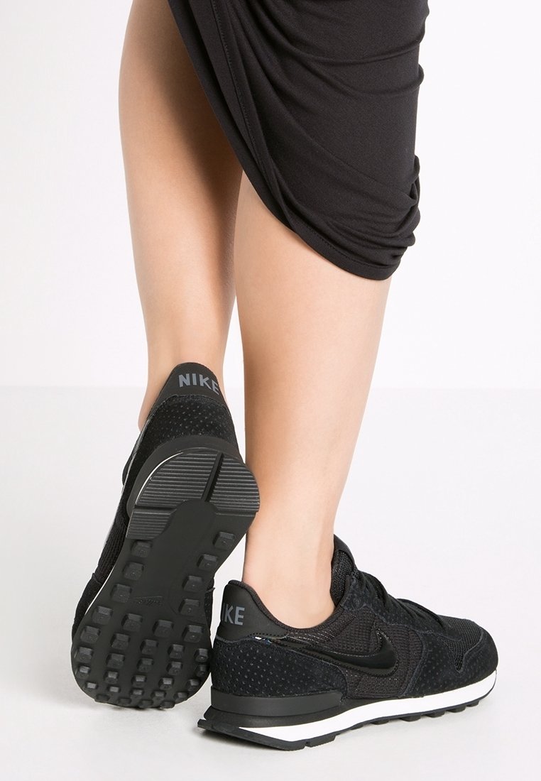 Svarta Nike-sneakers med texturerat mesh och mockadetaljer, med ett mönstrat sul och ett framträdande logo på hälen.