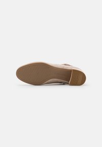 Beige nazouvací boty s hladkým, texturovaným svrškem a gumovou podrážkou. Obsahují jemné značení na podrážce a nízký, pohodlný design.
