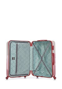 Valise rigide avec un extérieur rouge brillant. L'intérieur présente un revêtement matelassé bleu clair, une poche zippée et des sangles élastiques pour un rangement sécurisé.