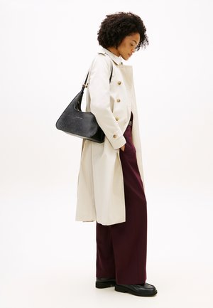 Lichtbeige trenchcoat met gouden knopen, gecombineerd met bordeauxrode brede pantalon en zwarte handtas, met gladde texturen en minimale patronen.