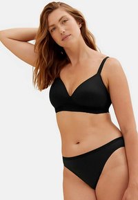 Svart underklädesset med en mjuk, vadderad bralette med spetskant och matchande bikiniunderkläder. Enkel design, modern form.
