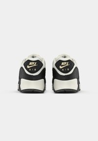 Mustvalge Nike Air tennisetal on tekstureeritud must konts, beeži aktsentide ja kuldse brändinguga. Omab pehmet vahevahendit mugavuse tagamiseks.