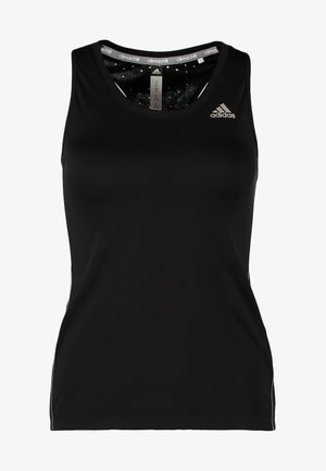 Kobieta idąca, ubrana w czarny bezrękawnik, szare legginsy trzy czwarte w panterkę oraz czarne buty sportowe.