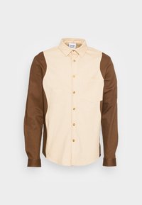 Skjorta med knappar som har en ljusbeige framsida och bruna ärmar, tillverkad av bomull, med en bröstficka och guldfärgade knappar.