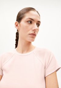 Lichtroze geribde t-shirt met korte raglanmouwen en een ronde halslijn, met een zachte textuur en minimalistisch ontwerp.