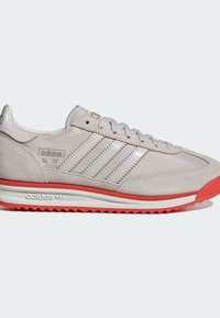 Baskets Adidas SL '72 en suède gris clair avec des rayures argentées, semelle blanche et semelle extérieure en caoutchouc rouge ; design à lacets.