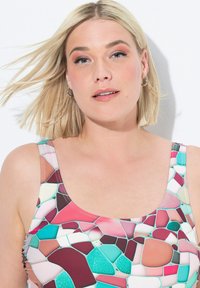 Tankini coloré avec un motif de mosaïque dans des teintes de rose, vert et bordeaux ; fabriqué en tissu lisse et extensible ; possède un décolleté en scoop.