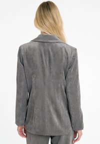 Grijze corduroy blazer met een gestructureerd ontwerp, lange mouwen, geknopt kraag en verticale ribbels. Eenvoudige achterkant met minimale details.