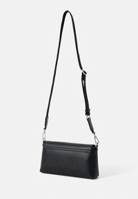 Čierna crossbody taška s textúrovaným povrchom, obdĺžnikovým tvarom, štíhlym dizajnom, nastaviteľným popruhom a striebornými kovovými doplnkami.
