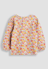 Langärmlige Bluse mit floralem Muster, die rosa, gelbe und orange Blumen auf weißem Hintergrund zeigt. Rundhalsausschnitt und Knopfdetail auf der Rückseite.