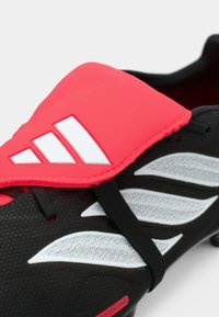 Μαύρο ποδοσφαιρικό παπούτσι με έντονο ροζ μπροστινό μέρος. Διαθέτει λευκές λεπτομέρειες, υφή επιφάνειας και άνετη εφαρμογή. Σχεδιασμένο για τεχνητούς χλοοτάπητες.