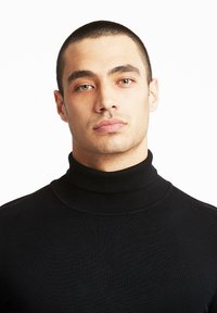 Črn turtleneck pulover iz rebraste pletenine, z visokim ovratnikom in prilegajočo se zasnovo, teksturiran z neprisiljenimi šivi.