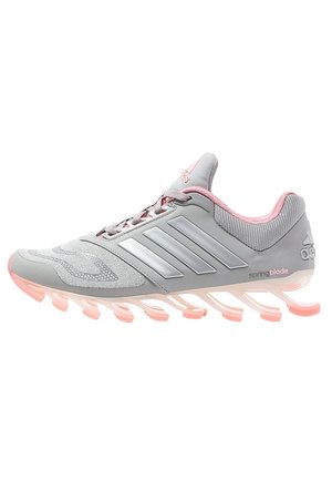 Chaussure de course Adidas Springblade grise et rose avec des lames de semelle segmentées et trois bandes argentées sur le côté.