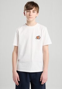White cotton t-shirt featuring a small orange embroidered graphic of a person running on the chest. Short sleeves and crew neckline.