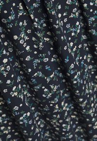Tela con un patrón floral sobre un fondo azul marino oscuro. Presenta flores blancas y azules con tallos verdes, textura suave y caída fluida.