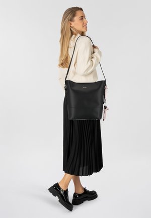 Borsa a spalla in pelle nera con una texture liscia e un design minimalista, dotata di una tracolla accentuante e staccabile in un colore a contrasto.