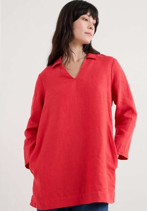 Red linen tunic with a V-neck, long sleeves, side pockets, and a relaxed fit, featuring a simple, unembellished design.