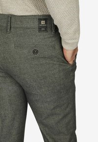 Graue Hose aus strukturiertem Stoff mit einer Gesäßtasche mit Knopfverschluss, einem Markenlabel am Bund und einer taillierten Passform.