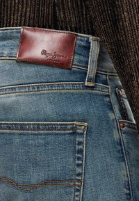 Μπλε τζιν από τζιν ύφασμα με δερμάτινη ετικέτα με την επιγραφή «Pepe Jeans London». Διαθέτει λεπτομέρειες ραφής και δύο πίσω τσέπες.