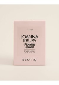 Różowe prostokątne pudełko perfum z wyraźną czarną etykietą z napisem „Joanna Krupa Feminine Power”, z informacjami o pojemności i marce na dole.