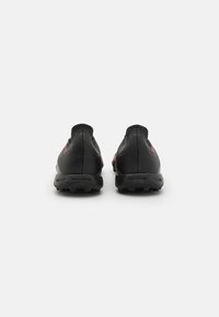 Scarpe da atletica nere con tomaia in pelle texturizzata, dettagli rossi a contrasto e suola in gomma. Progettate per le prestazioni con un profilo basso.