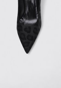 Escarpin noir à bout pointu avec une finition satinée élégante, présentant un motif discret de léopard et une texture intérieure lisse.