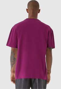 Kortärmad t-shirt med rund hals i magenta bomull. Har en avslappnad passform och slät yta. Inga synliga logotyper eller mönster.