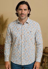 Langearm shirt met een lichtblauwe achtergrond en een bloemenpatroon in tinten bruin en blauw; knopen aan de voorkant, getailleerde pasvorm.