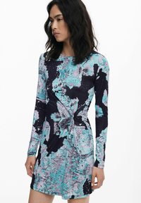 Langärmliges Kleid mit einem mehrfarbigen abstrakten Muster in Schwarz, Türkis und Grau. Hat ein geknotetes Detail an der Taille.