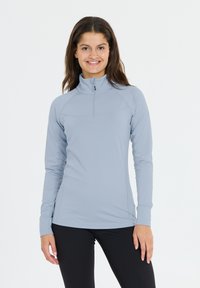 Vaaleansininen neljännesvetoketjullinen pitkähihaisnen paita, jossa on sileä pinta, sauman yksityiskohtia ja muotoiltu malli, yhdistettynä mustiin legginseihin.