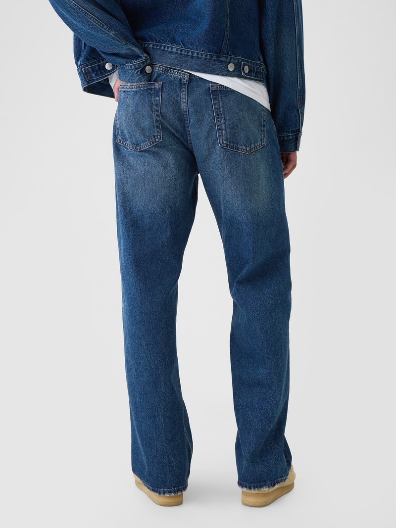 Dunkelblaue Jeans aus Denim mit lässiger Passform, die über zwei Gesäßtaschen und einen ausgefransten Saum verfügt. Der Stoff hat eine leicht ausgewaschene Textur.
