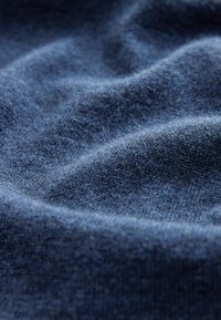 Marineblauer Stoff mit einem weichen, strukturierten Strickmuster, das sanfte Wellen und Falten aufweist und Flexibilität sowie Komfort signalisiert.