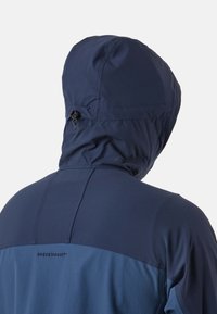 Persoon die een marineblauwe capuchonjas draagt met verstelbare trekkoord aan de achterkant, gezien van achteren.