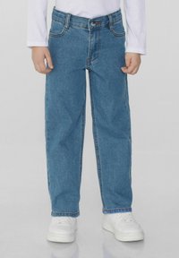 Modré džíny z denimu se střihem rovného nohavice, jemným šitím, předními kapsami a zapínáním na knoflík, spárované s bílými teniskami.