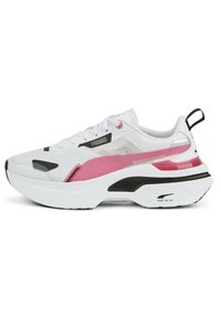 Baskets blanches de sport avec superpositions en mesh et synthétique, ornées d'accents roses et noirs, une semelle épaisse et une languette de traction à l'arrière.