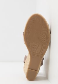 Sandale à talon compensé avec une semelle extérieure brune texturée, un matériau en jute sur le talon et un dessus en tissu gris doux avec une sangle réglable. Taille 37.